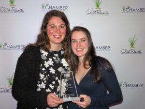 two women standing next to each other holding an award