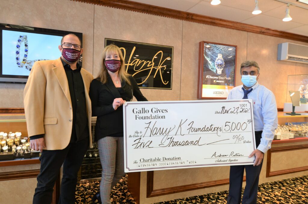 three people wearing masks holding a large check