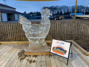 a glass chicken statue sitting on top of a wooden deck