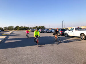 a group of bicyclists riding through a parking lot