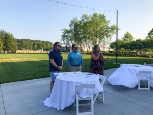three people standing around a table with white cloths