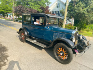 an old fashioned blue car driving down the street