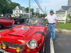 a man standing next to a red convertible car