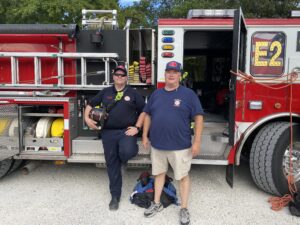 two men standing in front of a fire truck
