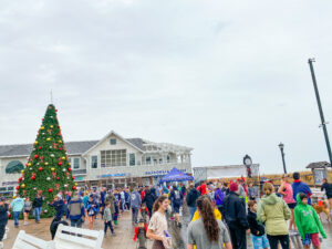 a crowd of people walking around a christmas tree