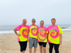 four people wearing bright colored shirts on the beach