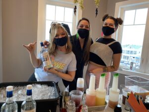 three women wearing face masks and holding bottles