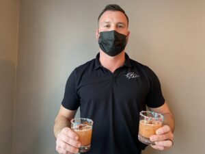 a man wearing a face mask holding two glasses