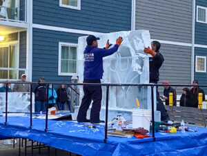 two men standing on a table with an ice block