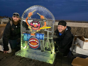 two men pose for a picture in front of an ice sculpture