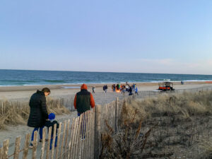 people are walking on the beach near a fence