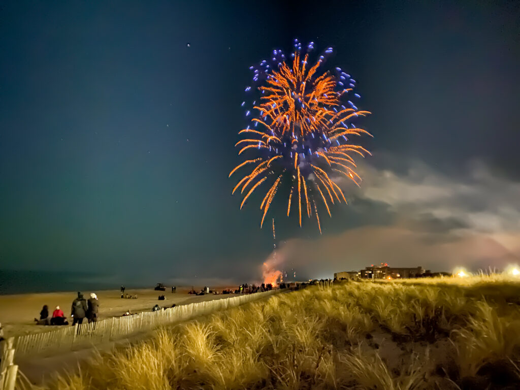 fireworks are lit up in the night sky over a beach