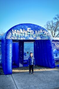 a young boy standing in front of an inflatable winter maze