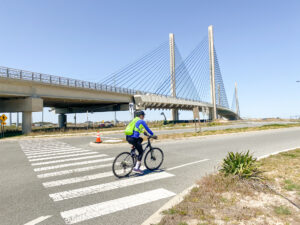 a man riding a bike across a street under a bridge