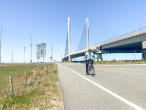 a man riding a bike down a road under a bridge