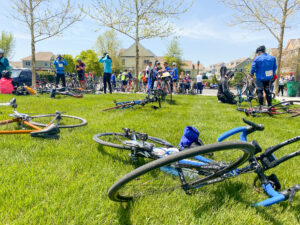 a group of bicyclists gather around their bikes on the grass