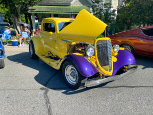 a yellow and purple car parked next to other cars