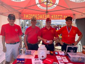three men in red shirts standing under a tent