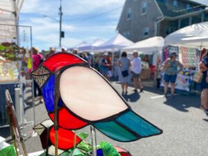 a colorful stained glass bird on display at an outdoor market