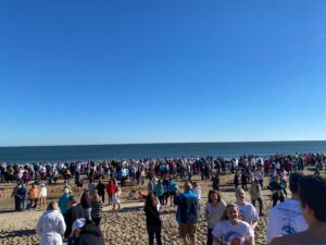 a large group of people standing on top of a sandy beach