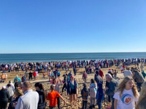 a large group of people standing on top of a sandy beach