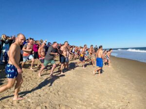 a large group of people are running on the beach