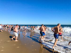 many people are running on the beach near the water