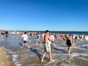 many people are walking in the water at the beach