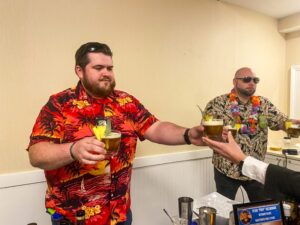 two men in hawaiian shirts toasting with drinks