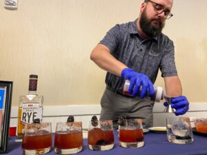 a man in blue gloves pours some liquid into glasses