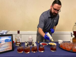 a man pouring syrup into glasses on a table