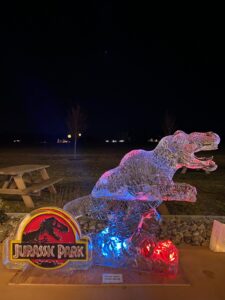 a lighted sculpture of a dinosaur on top of a rock
