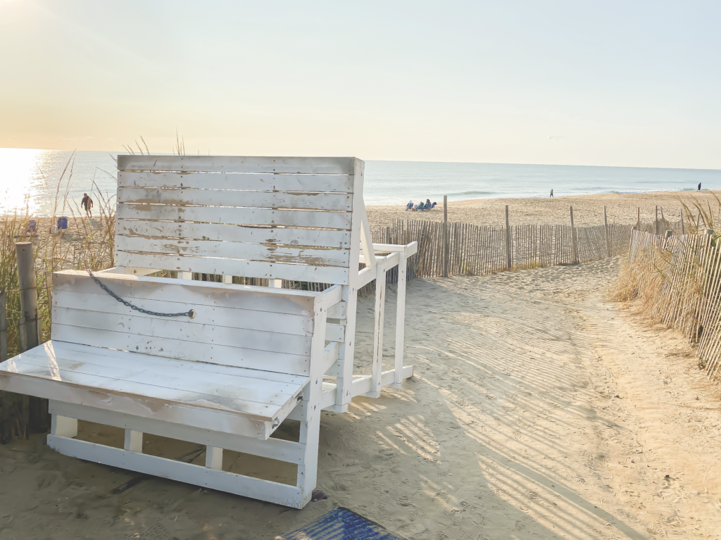 a white bench sitting on top of a sandy beach