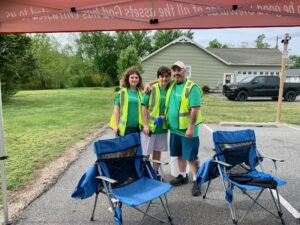 three people in safety vests standing under a tent
