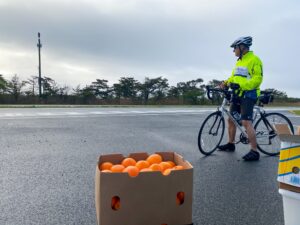 a man riding a bike next to a box of oranges