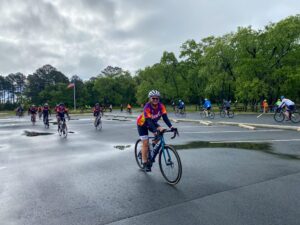 a group of bicyclists riding down a wet road