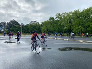a group of bicyclists riding down a wet street