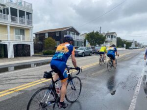 three bicyclists riding down the street in the rain