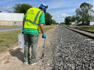 a man in a safety vest is walking on the railroad tracks
