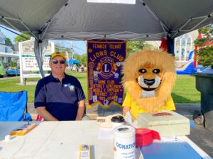 two men sitting at a table with a lion mascot