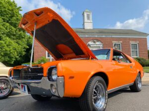 an orange muscle car with its hood open