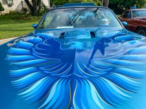 a blue car with a bird painted on the hood