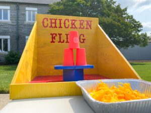 a yellow chicken float next to a container of fries