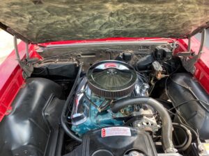 the engine compartment of a red car with its hood open