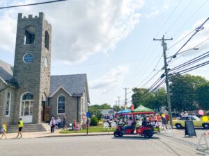 a small car driving down a street past a church