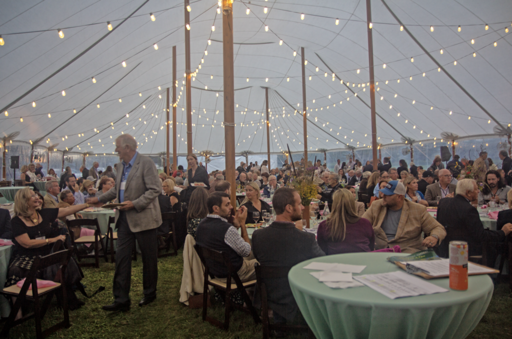 a large group of people sitting at tables in a tent