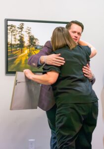 two people hugging each other in front of a painting