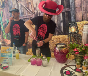 two men in hats are making drinks at a table