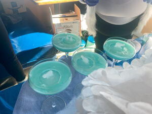 three glasses with blue liquid sitting on a table