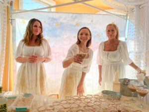 three women in white dresses standing behind a table
